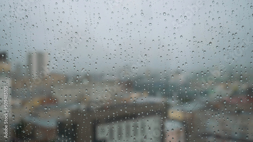 Rain drops on glass with a background. Stock footage. Raindrops on the window on the background of the city