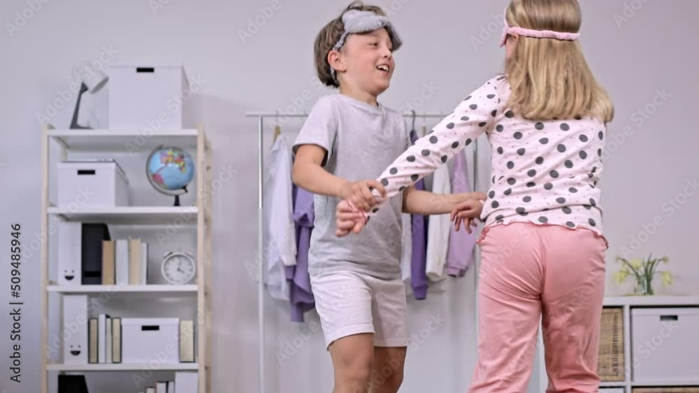 Sister and brother dressed in pyjamas are dancing together. Slow motion.