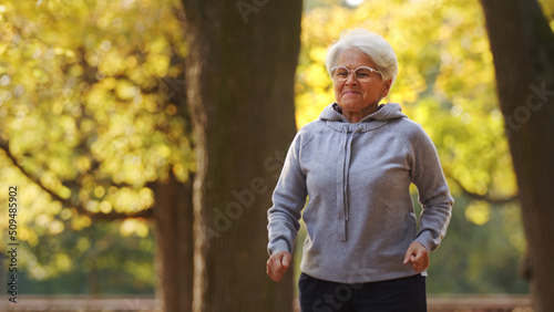 senior grey haired woman runs jumps park background medium shot copy space . High quality photo