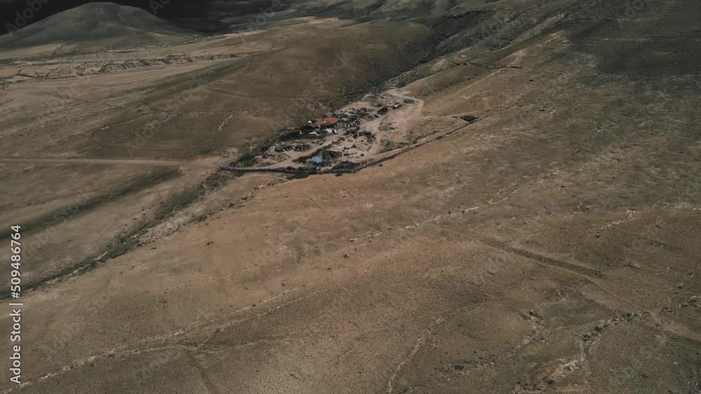 Wild camping in the desert dunes on hot sunny day in Fuerteventura Canary Islands. Mad Max style junkyard in sand. Mars like landscape drone zoom in. Wild camping in the desert dunes on hot sunny day in Fuerteventura Canary Islands. Mad Max style junkyard in sand. Mars like landscape drone zoom in.