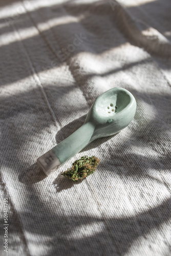 handmade green ceramic pipe with a bud next to it