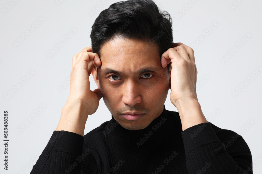Headshot of Asian man touches his face looking at the camera. Mental health. Headshot of Asian man touches his face looking at the camera. Mental health.