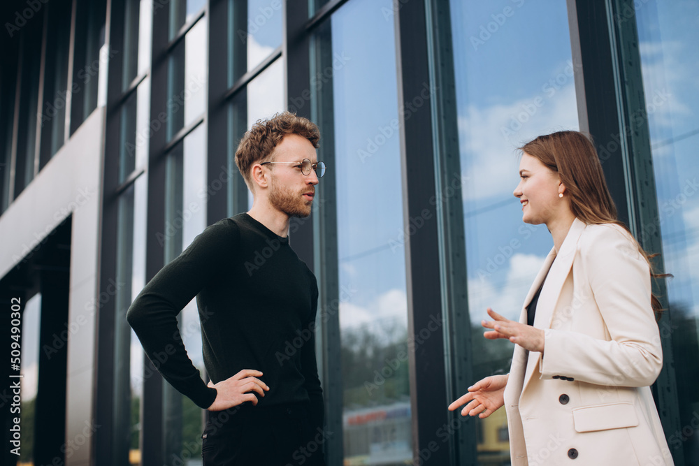 Businessman and woman walking and talking outside office Businessman and woman walking and talking outside office