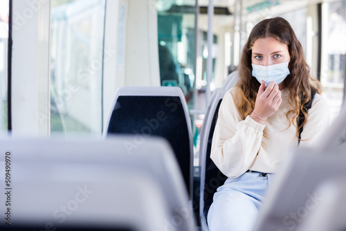 Portrait of a focused girl in a protective mask, riding on public transport during the pandemic on business photo