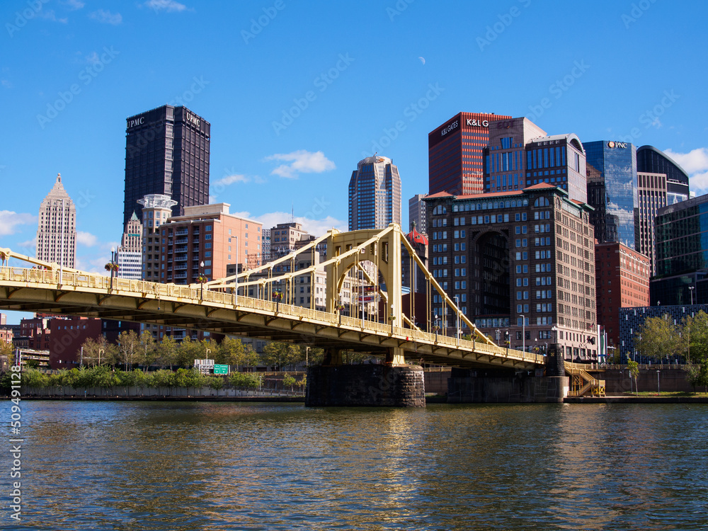 Naklejka premium Yellow bridge and Pittsburgh downtown against blue sky.