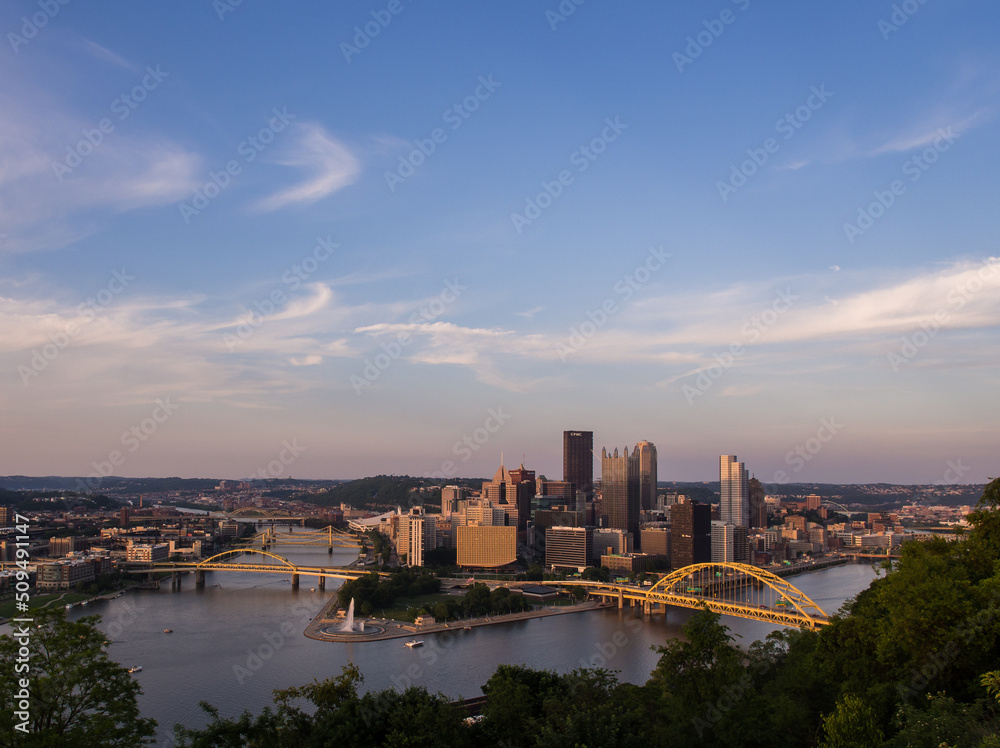 Pittsburgh (PA) skyline, Point State Park and yellow bridges across the Allegheny and Monongahela Rivers at sunset with beautiful sky.