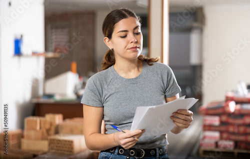 Portrait of young woman owner of renovating house reading documents at construction site