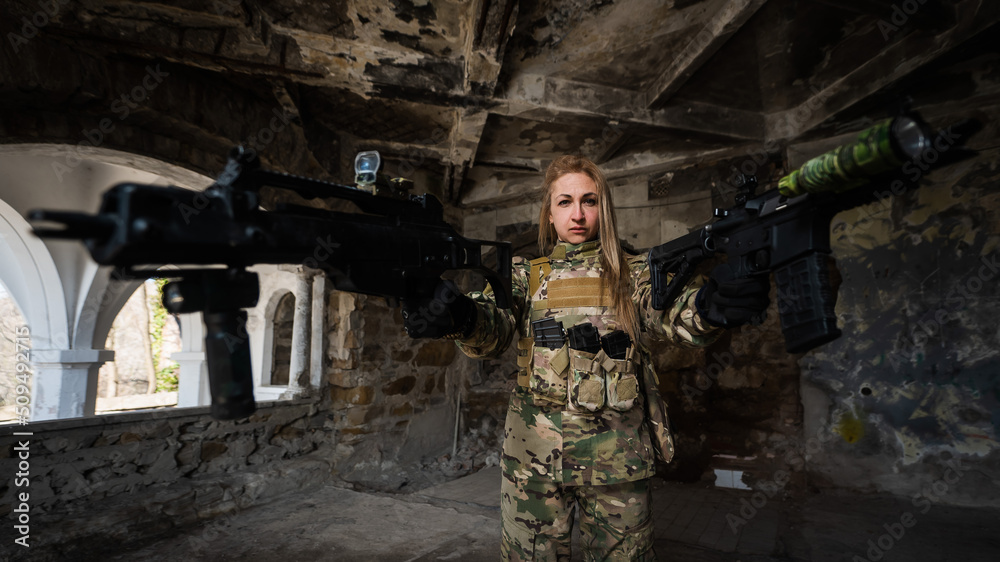 Caucasian woman in army uniform holding two machine guns. Caucasian woman in army uniform holding two machine guns.