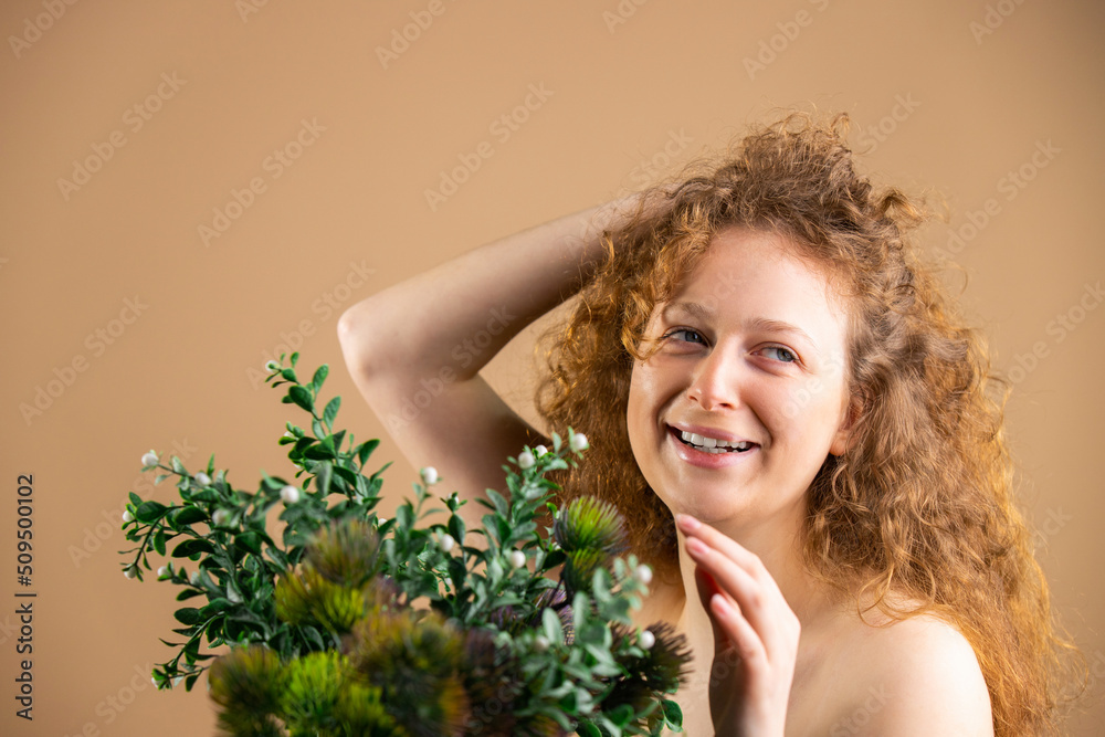 Portrait of a beautiful young woman with red hair and natural makeup with a bouquet of green flowers in front of her. Portrait of a beautiful young woman with red hair and natural makeup with a bouquet of green flowers in front of her.
