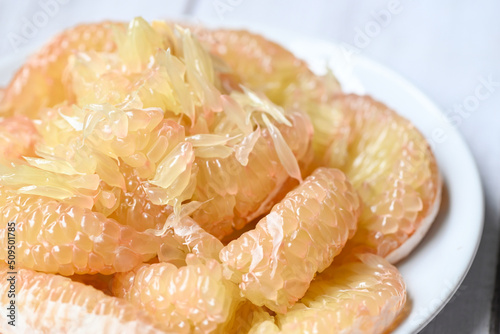 Cloce up pomelo fruit on white plate, fresh pomelo peeled on frome pomelo tree , pummelo , grapefruit in summer tropical fruit  in thailand photo