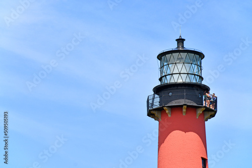 Tourists enjoying the views from atop of the Jupiter lighthouse against clear blue skies at Jupiter Inlet, Florida	 photo