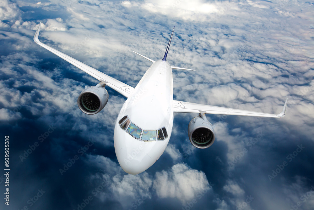 Fototapeta premium Passenger plane in flight. Aircraft fly high in the sky above the clouds. Front view. Right heeling.