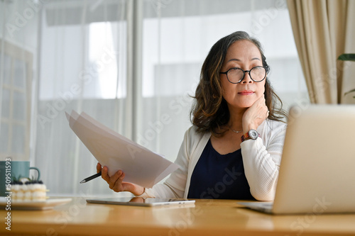 Concentrated asian middle aged female businesswoman using portable computer photo