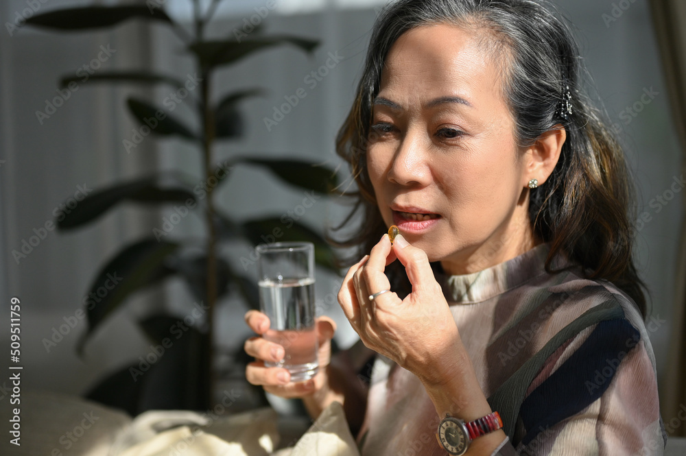 Healthy asian aged woman taking a vitamin pill or taking a medicine. healthcare concept Healthy asian aged woman taking a vitamin pill or taking a medicine. healthcare concept