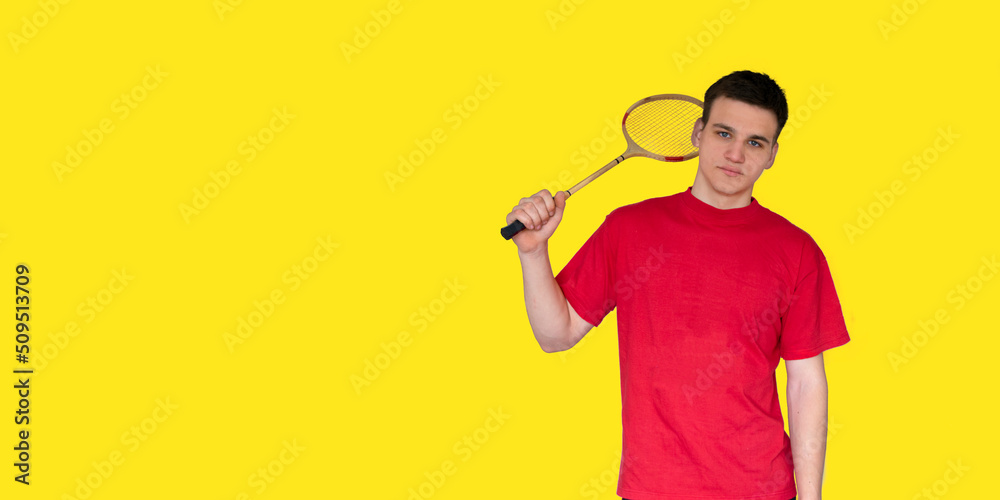 Portrait of an caucasian man holding a badminton racket on a yellow background Portrait of an caucasian man holding a badminton racket on a yellow background