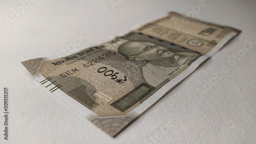 One single new Indian five hundred rupee currency note isolated on white table background with copy space. Horizontal closeup macro side view. Pay, payment, savings, purchase, price and money concept. photo