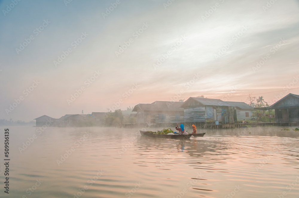 Two women rowing into the fog in Borneo