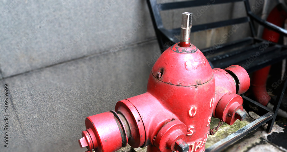 Photo of a red hydrant in front of a building, the function of this tool is as a source of water when extinguishing fires by firefighters Photo of a red hydrant in front of a building, the function of this tool is as a source of water when extinguishing fires by firefighters