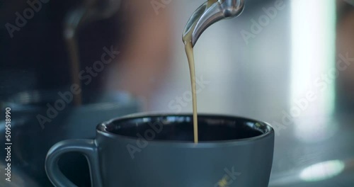 Fresh espresso coffee pouring from coffee machine into a mug