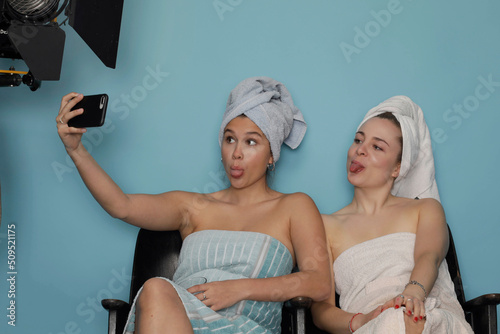 Two young woman waiting a model job to start and taking fun selfies