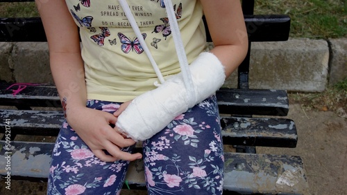 child with bandaged gypsum left hand hangind on the neck photo