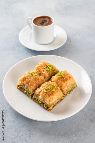 Pistachio baklava on a white plate with Turkish coffee.Traditional Turkish baklava and t coffee on a white background