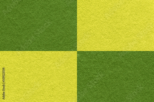 Texture of craft green and yellow paper background with cells pattern, macro. Structure of vintage olive cardboard.