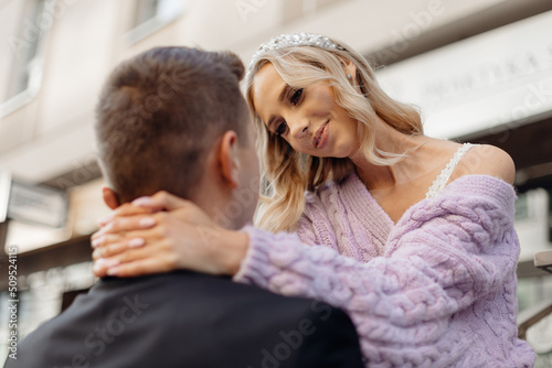 Beautiful young wedding couple in elegant clothes walk around city, smile and hug on street background. Portrait back view closeup of happy bride and groom in love. Wedding day, family holiday