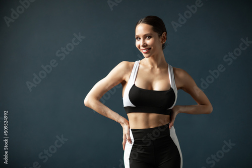 Happy young woman in sportswear smiling. Muscular fitness model