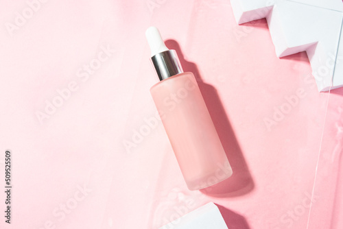 Pink Cosmetic bottle serum with pipette on pink background with podiums for Mock-up concept . copy space.top view