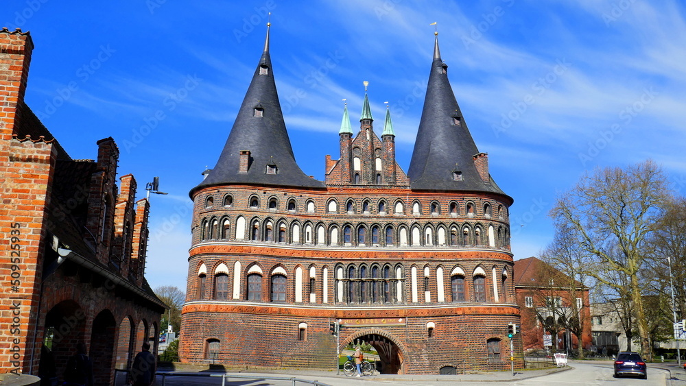 altes Lübecker Holstentor aus Backstein mit zwei Spitztürmen am Stadteingang unter blauem Himmel