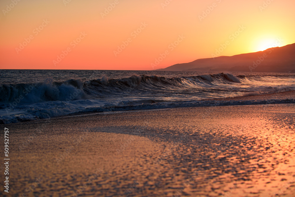 Landscape of sea and tropical beach at sunset or sunrise time for leisure travel and vacation. Reflection of sun in the water and sand on beach. Ocean waves background.