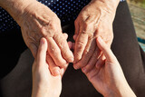 Close-up of daughter's hand holding hands of mother, grandmother.