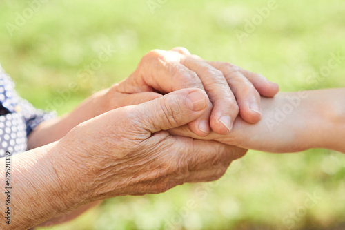 Gentle gesture of the hand of the grandmother holds the hand of the granddaughter. © evafesenuk