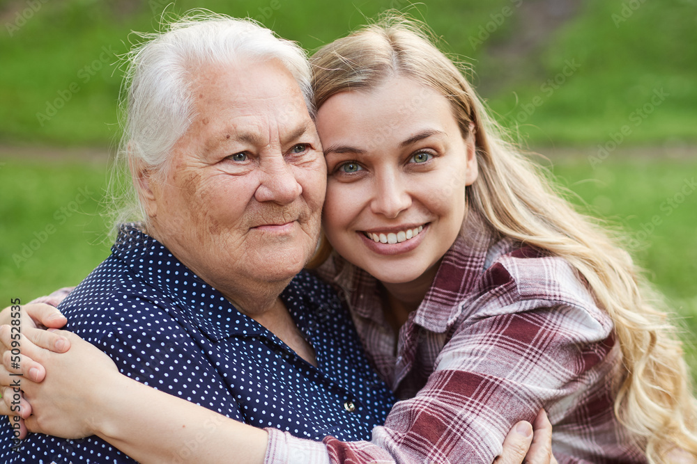 Cheerful smiling granddaughter hugging her grandmother. The connection of generations, love, care in the family Cheerful smiling granddaughter hugging her grandmother. The connection of generations, love, care in the family
