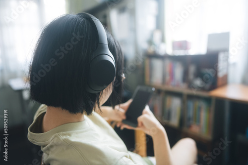Young adult asian woman wear headphone listen music and relax at home