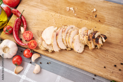 Sliced grilled chicken breast on wooden cutting board
