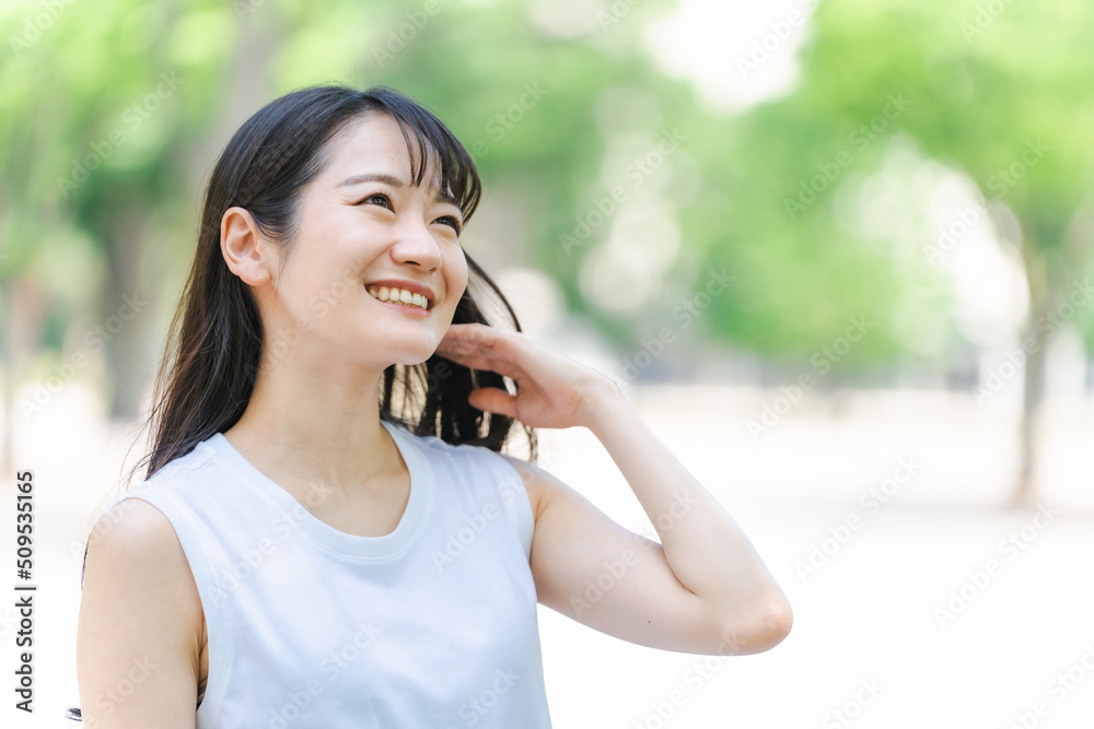 緑の中で黒髪をなびかせる女性
