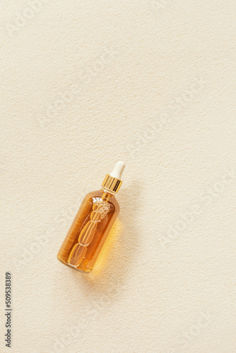 Serum or liquid collagen dropper bottle on sand background with sunlight and shadow with caustic effect. Anti age cosmetics products. Skin care beauty products, summer concept. Above view photo