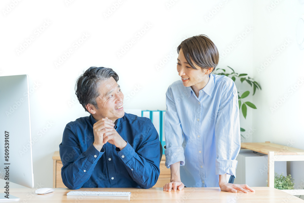 Fototapeta premium パソコンの前で話す二人の日本人男女