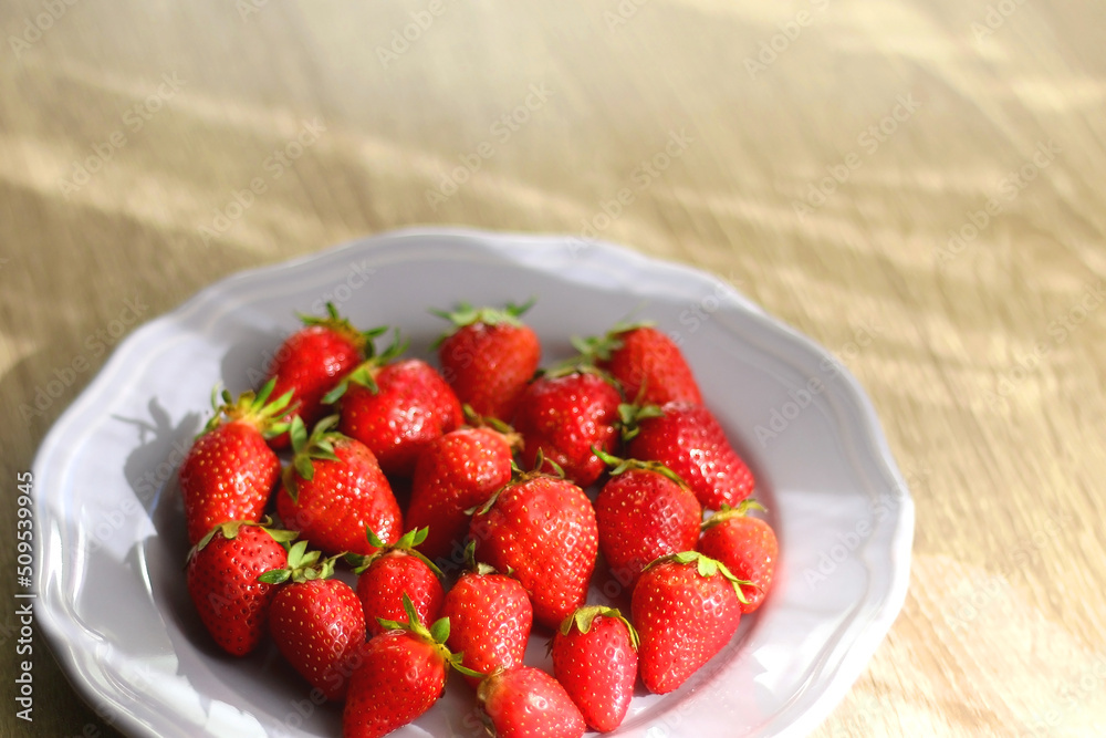 Lilac plate full of fresh strawberries on wooden table. Selective focus. Lilac plate full of fresh strawberries on wooden table. Selective focus.