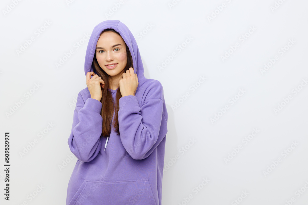 a relaxed woman stands on a gray background in a purple tracksuit wearing a hood on her head holding her neck with both hands a relaxed woman stands on a gray background in a purple tracksuit wearing a hood on her head holding her neck with both hands