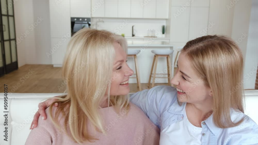 Happy smiling senior woman mother and her grown up daughter make heart shape hand gesture, sitting on sofa at home. Family love concept Happy smiling senior woman mother and her grown up daughter make heart shape hand gesture, sitting on sofa at home. Family love concept