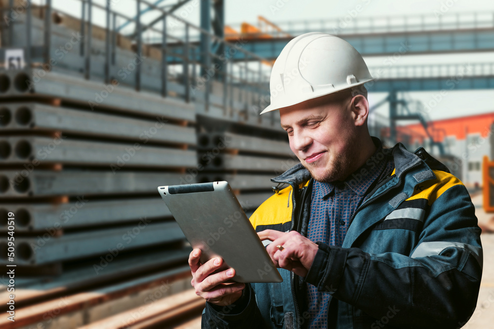 civil engineer with a tablet in his hands stands in the warehouse of finished products of a factory for the production of reinforced concrete products civil engineer with a tablet in his hands stands in the warehouse of finished products of a factory for the production of reinforced concrete products