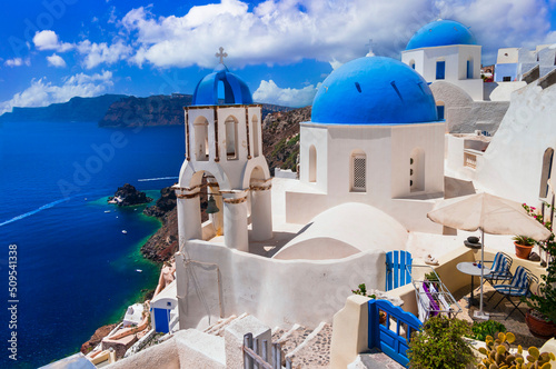 Iconic view with blue domes churches and caldera of most beautiful island - Santorini, Oia village, Cyclades . Greece