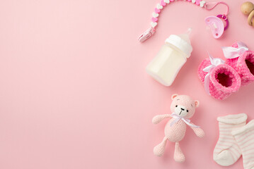 Baby accessories concept. Top view photo of pink booties socks knitted teddy-bear toy pacifier chain wooden rattle and bottle on isolated pastel pink background with copyspace