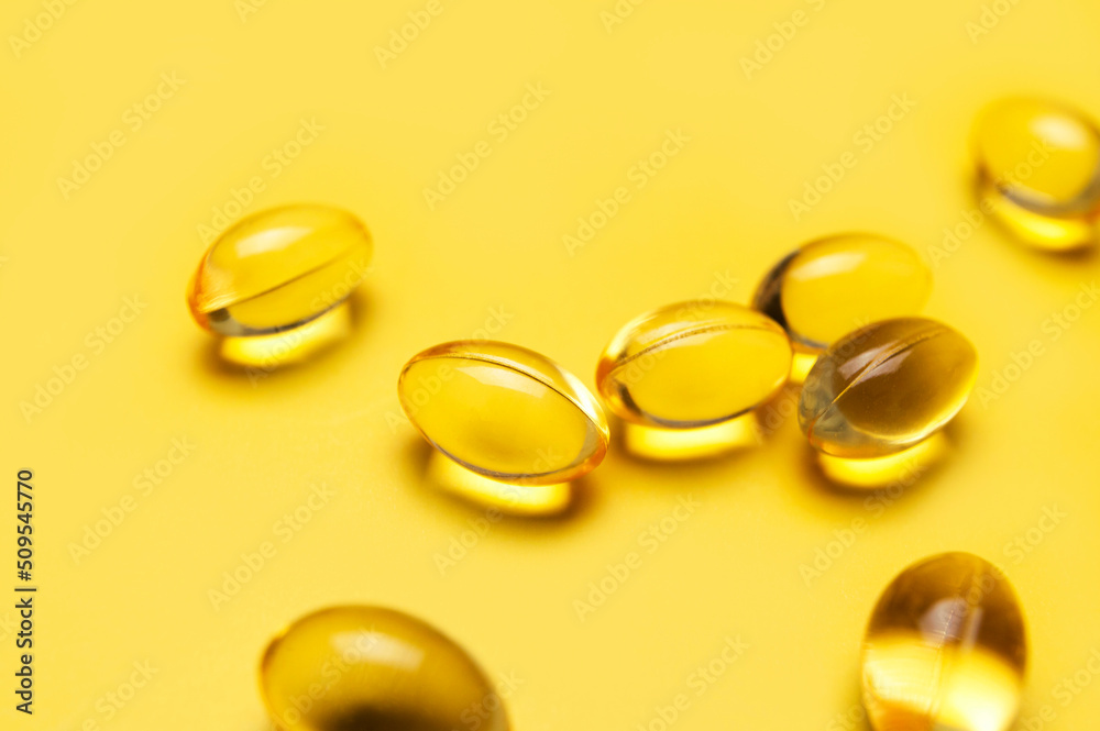 Capsules pill with vitamin D on yellow background close-up. Fish oil, Omega, Omega-3, dietary supplement, sunshine vitamin. Healthy lifestyle, medicine, cosmetology, diet. Pharmaceutical concept Capsules pill with vitamin D on yellow background close-up. Fish oil, Omega, Omega-3, dietary supplement, sunshine vitamin. Healthy lifestyle, medicine, cosmetology, diet. Pharmaceutical concept