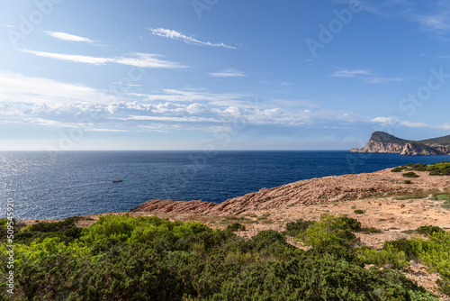 View from Cap Negret on coastline ending Cap Nuno, rushing light clouds in blue sky. Ibiza, Balearic Islands, Spain photo