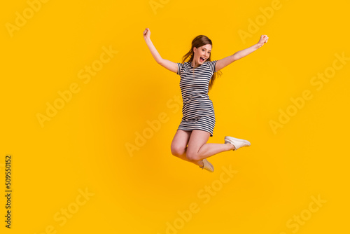 Full length photo of young excited girl jump up celebrate luck awesome champion isolated over yellow color background photo
