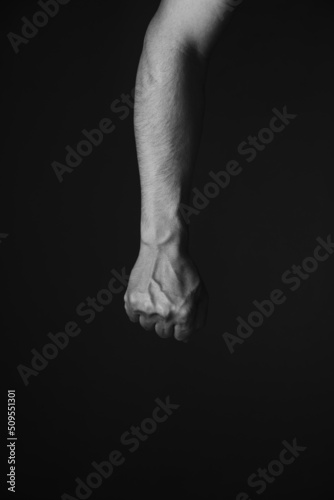 Brutal mans hand with protruding veins, black background.Black and white photo.